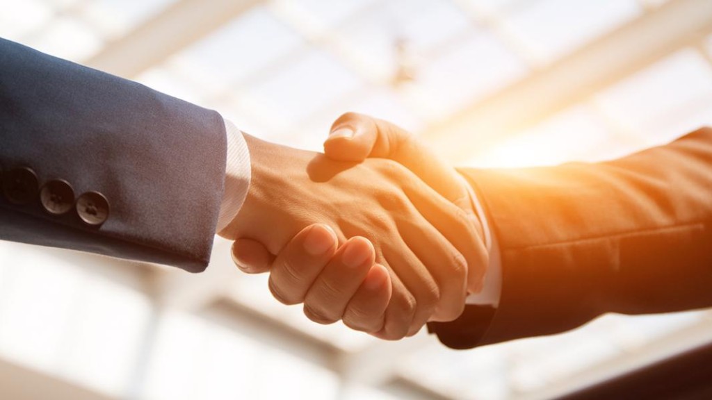 Hai người bắt tay trong văn phòng có ánh sáng tự nhiên